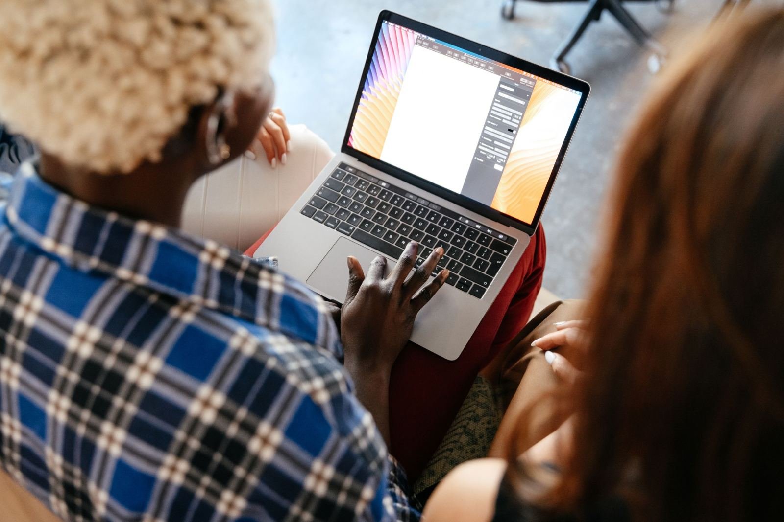 Two people look at a laptop screen together from behind