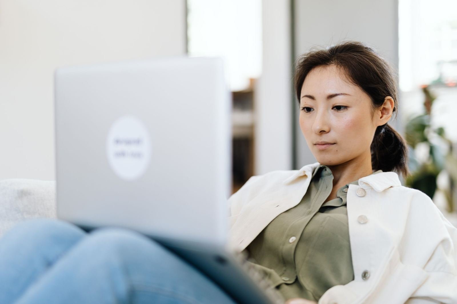 A woman looks at a laptop screen while sitting at home
