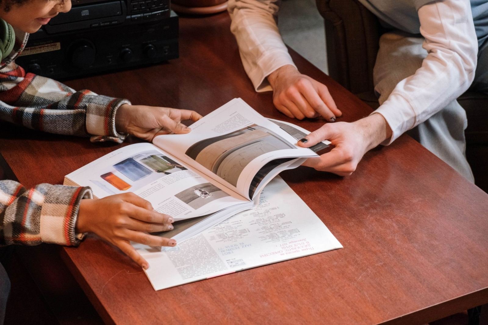 Two people review a printed brochure together at a wooden table