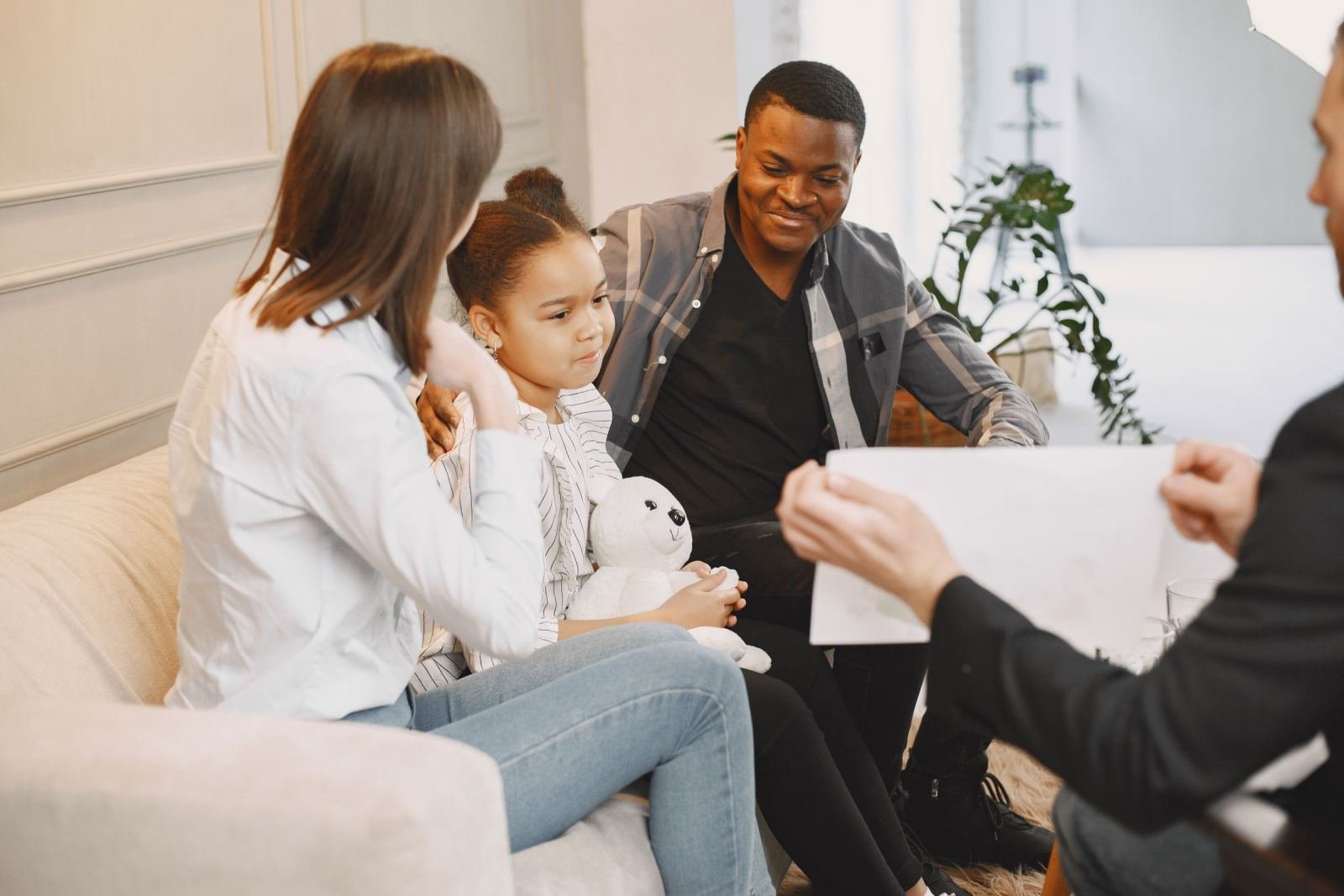 A family sits on a sofa while a therapist holds up a piece of paper