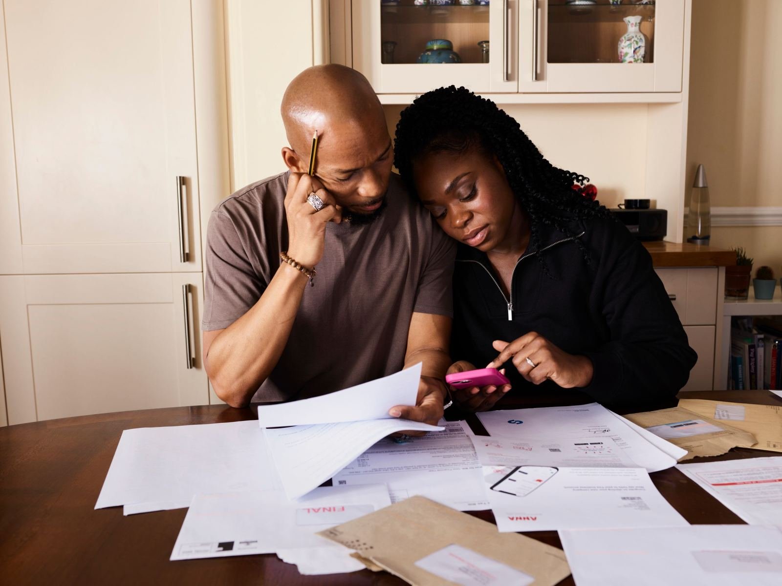 A man and woman review paperwork and a smartphone together at a table