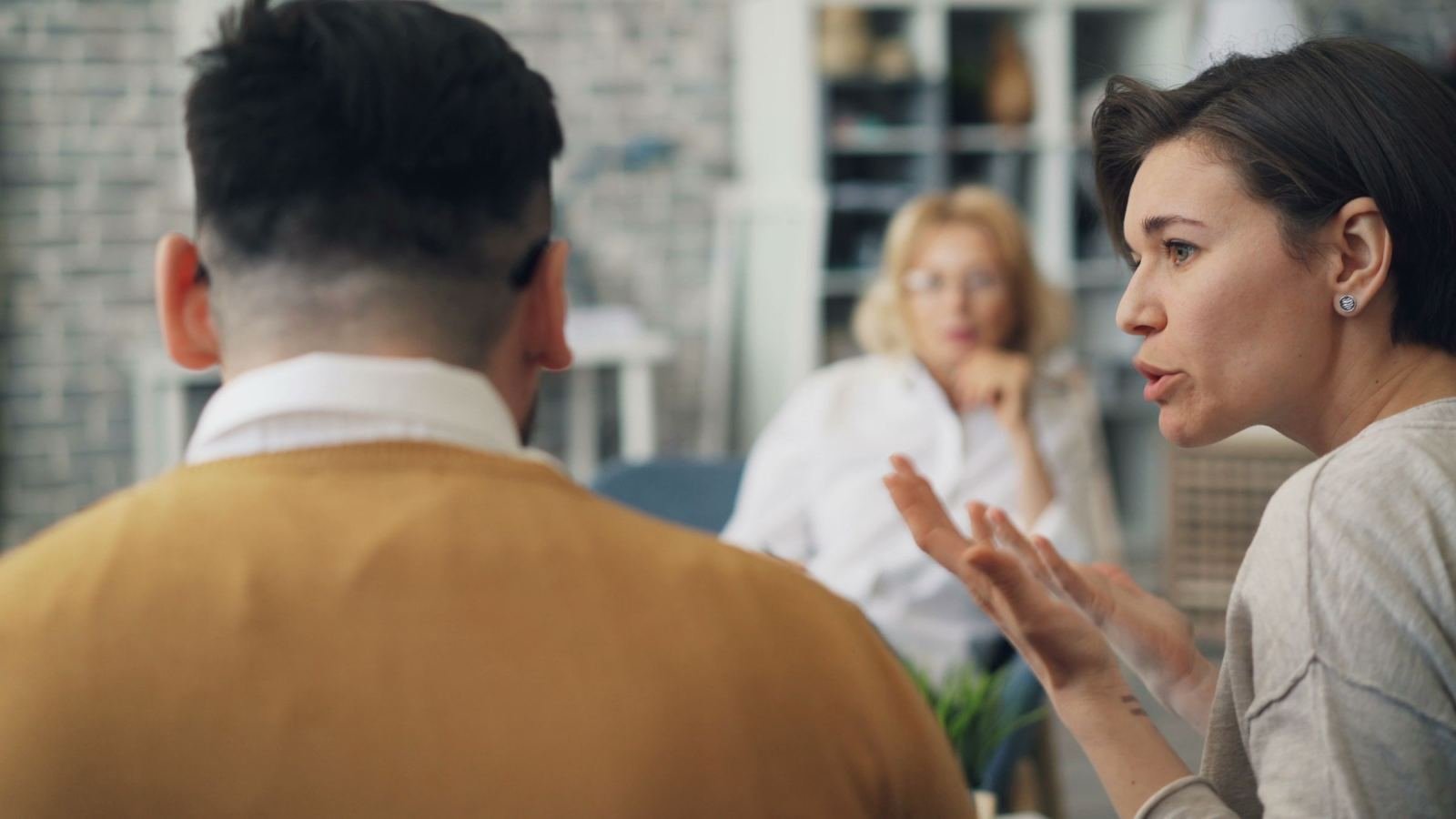A woman gestures while speaking to a man in a professional office setting