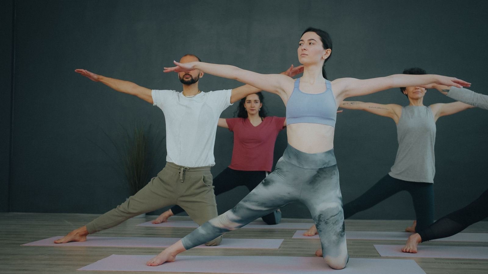 A group of adults practicing yoga poses on mats in a studio