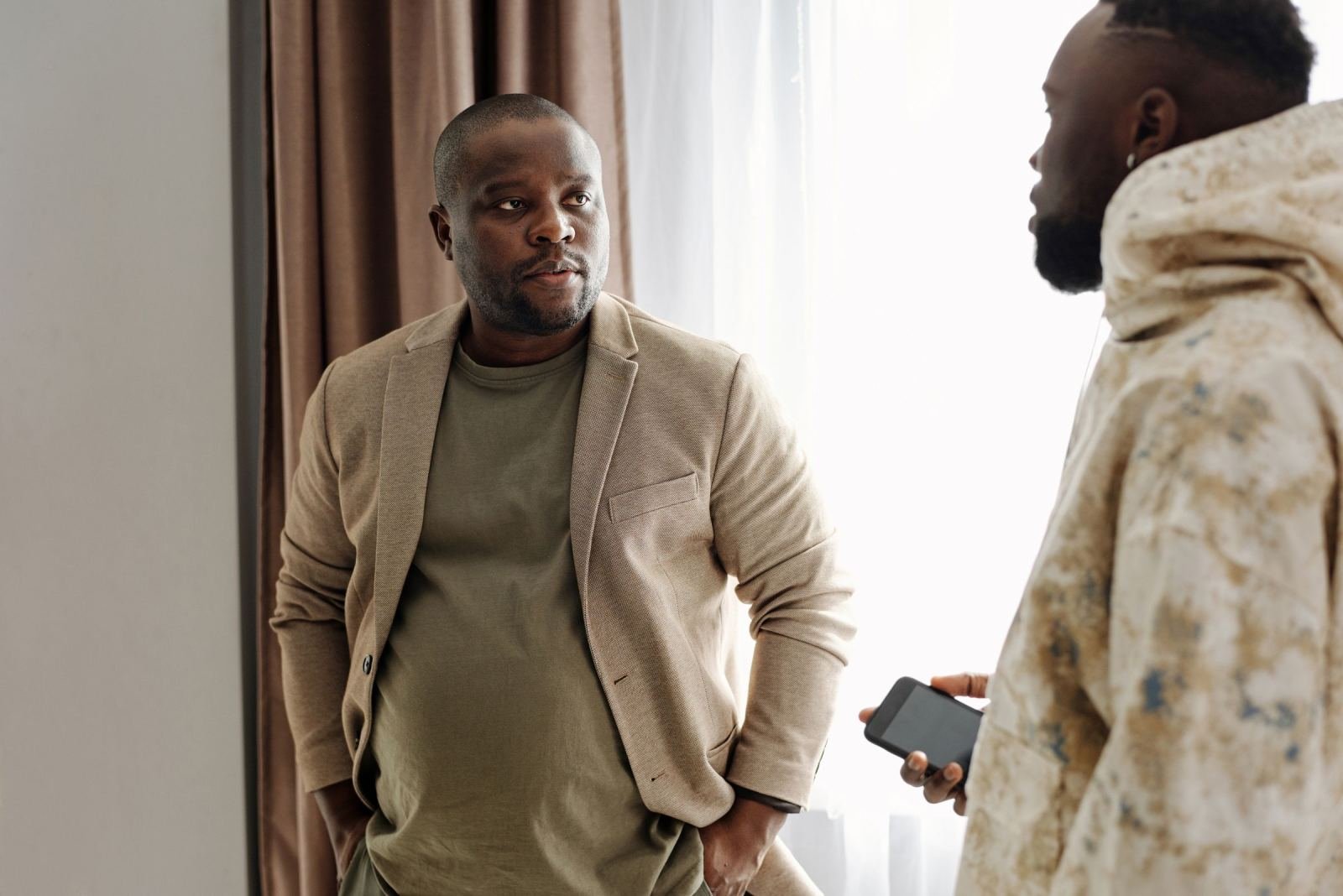 Two men stand and talk to each other in a bright room