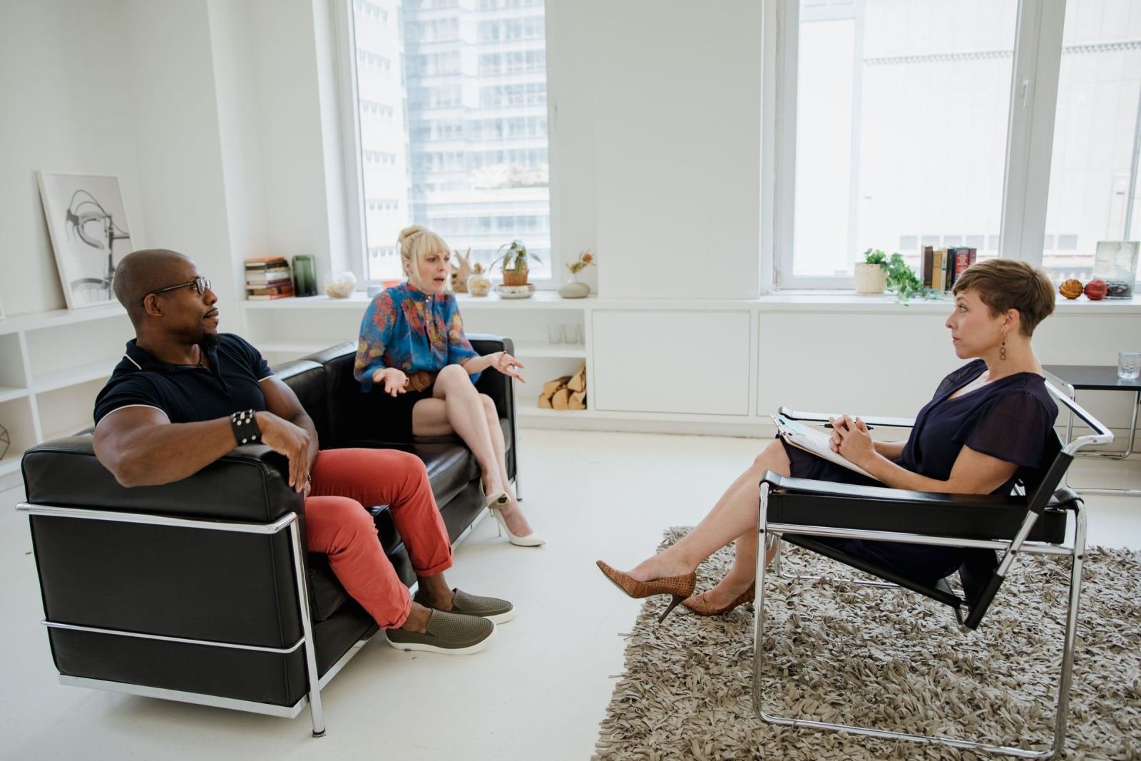 A counselor with a clipboard speaks with a man and woman in a bright office
