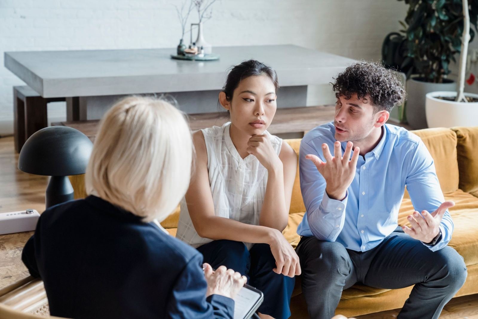 A couple talks with a counselor in a bright room