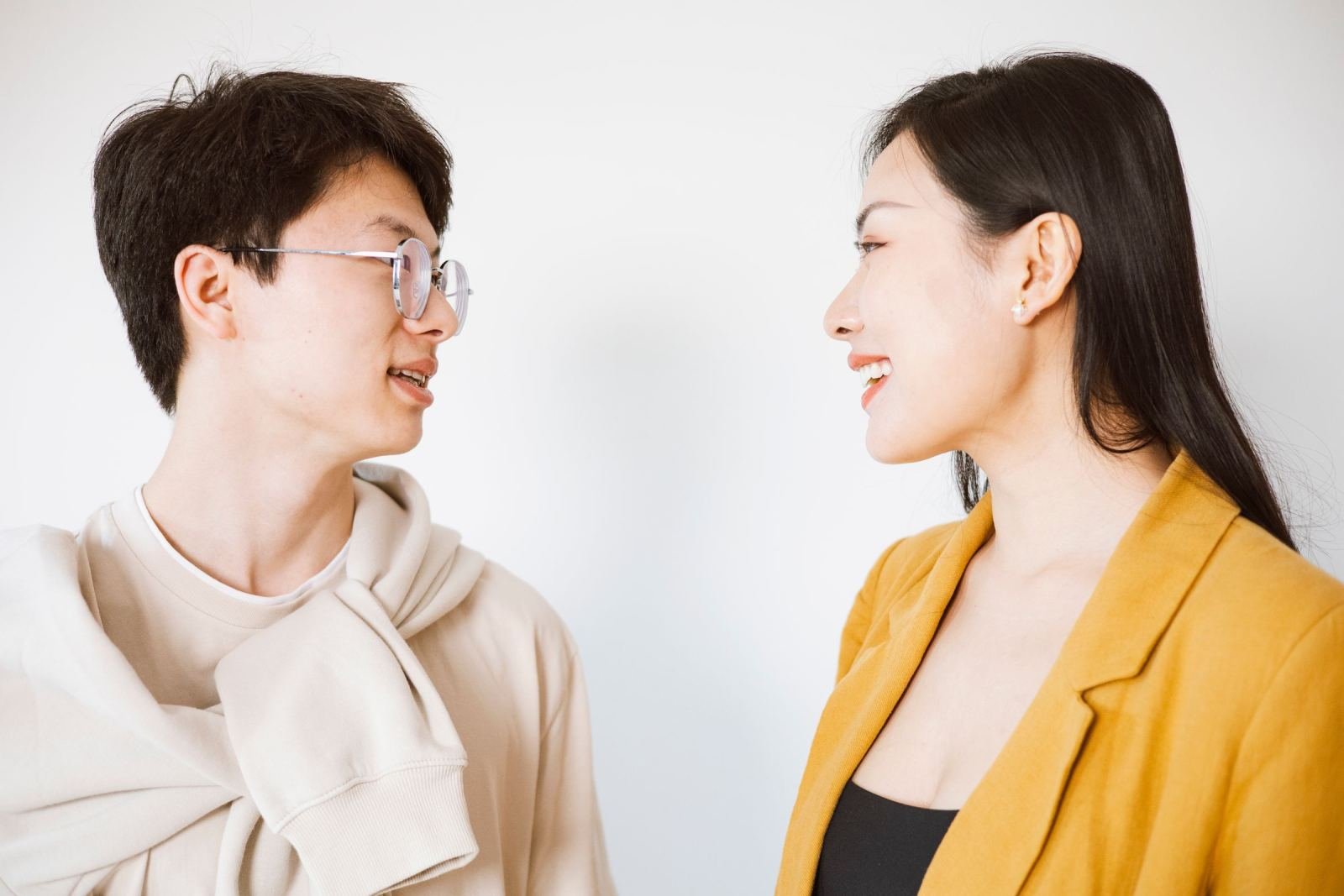 A man and a woman talk face-to-face on a white background