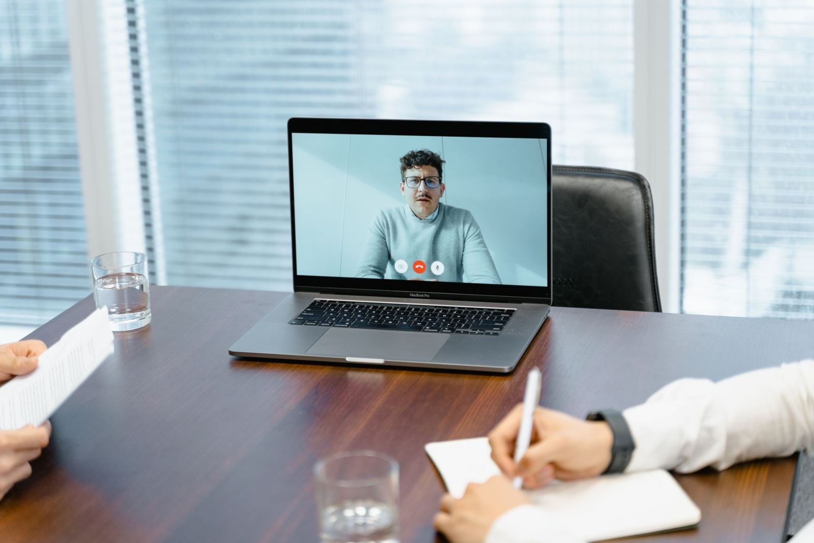 A person takes notes during a telehealth appointment on a laptop
