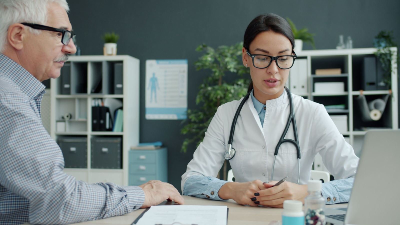 A doctor in a white coat talks with a patient in a medical office