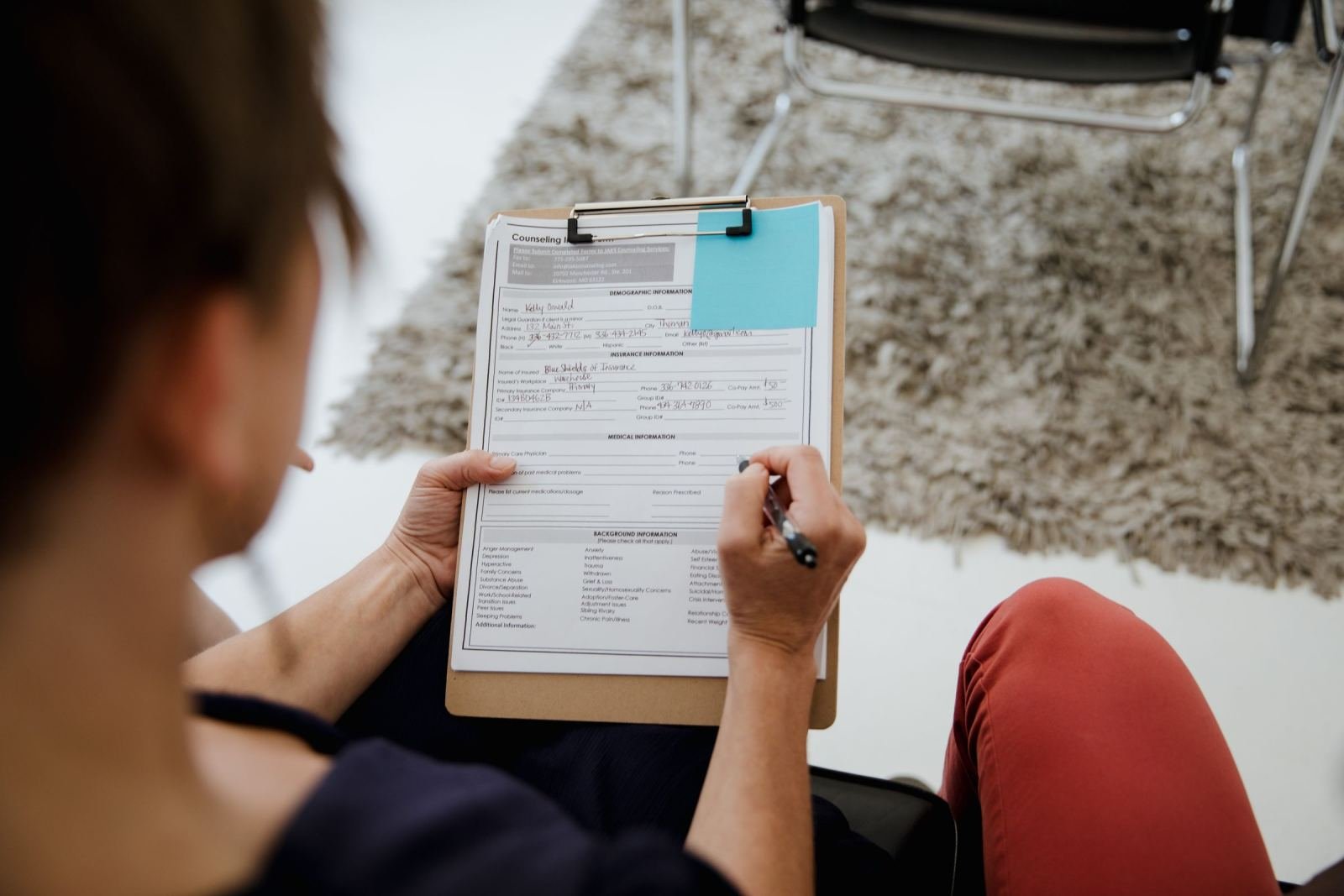 A person writing on a medical intake form on a clipboard