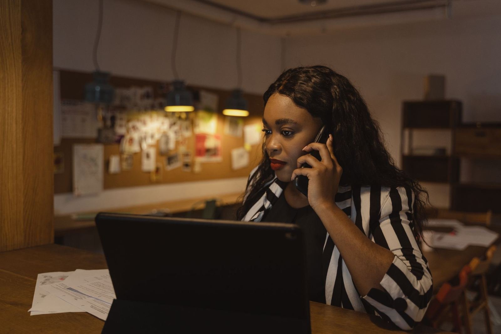 A woman on a phone call looks at a laptop screen at a desk