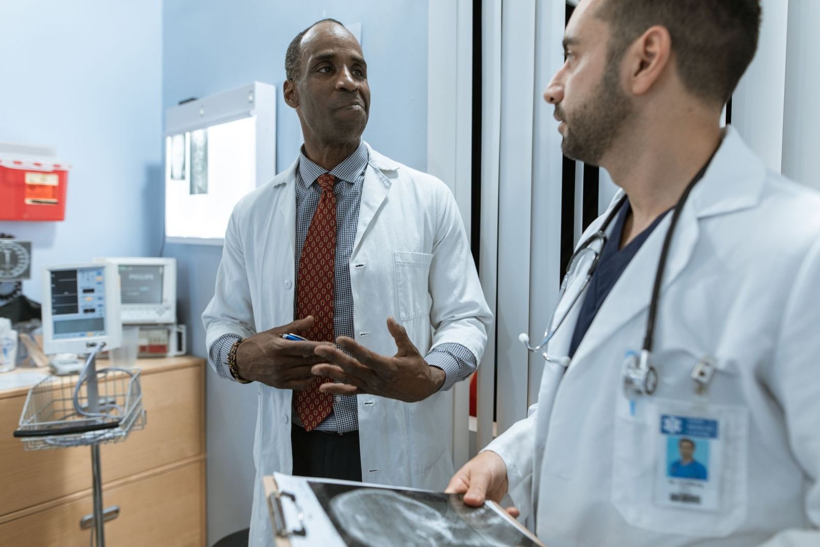 Two doctors in white coats discuss a patient's X-ray in a clinic