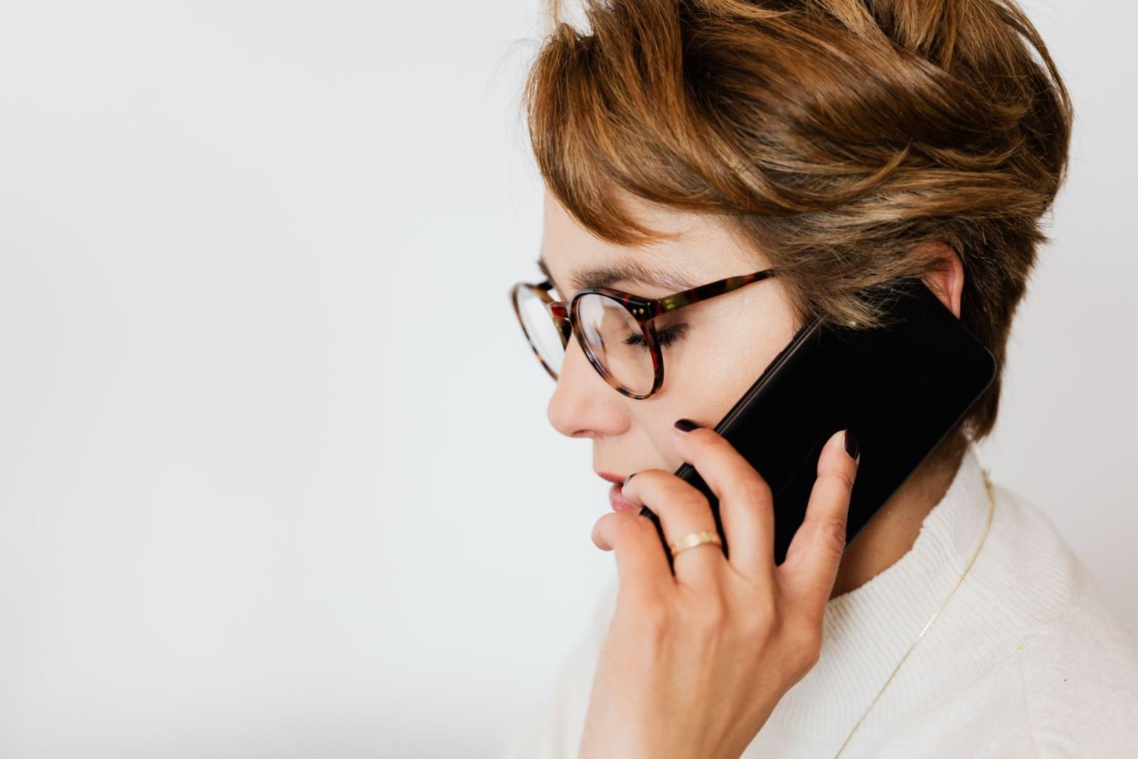 A person with glasses talking on a black smartphone