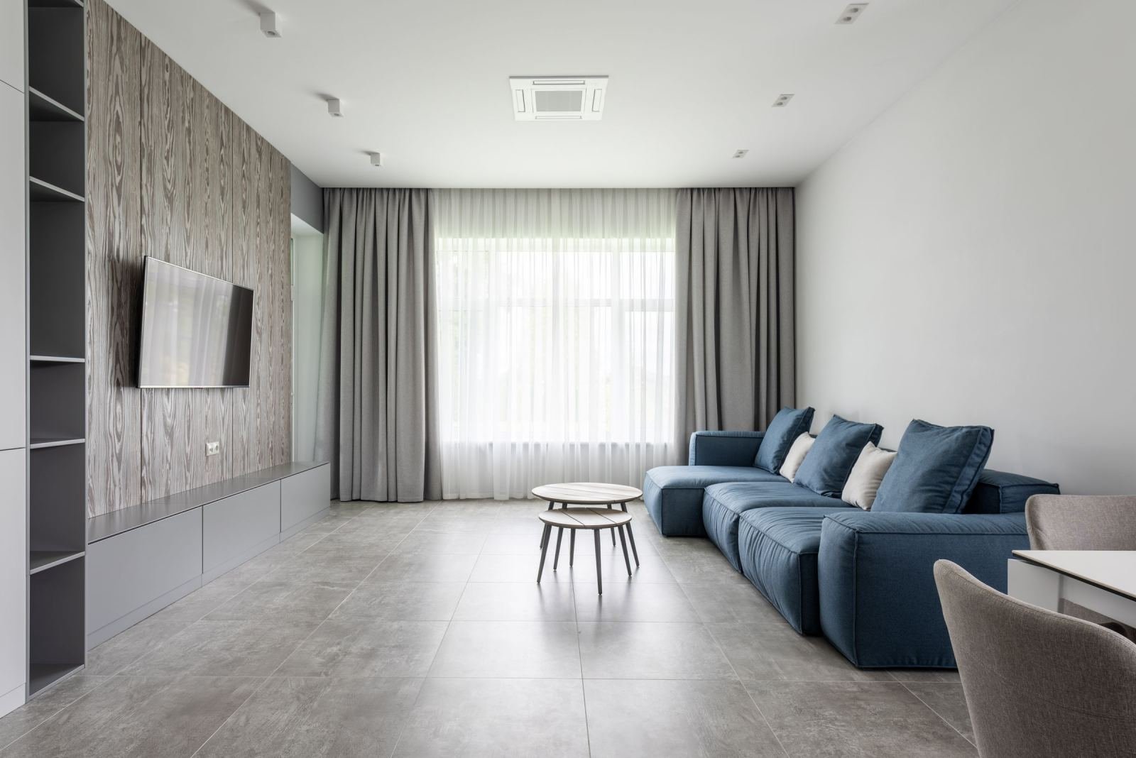 A bright modern common room with a blue sectional sofa and wood-paneled wall