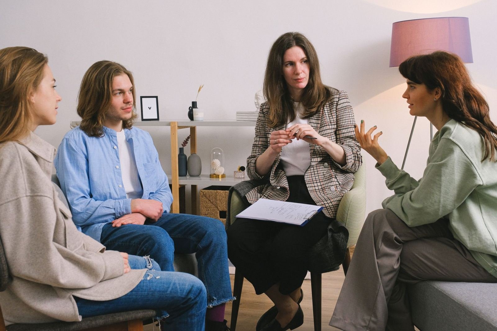 A counselor in a plaid blazer talks with three people in a bright office