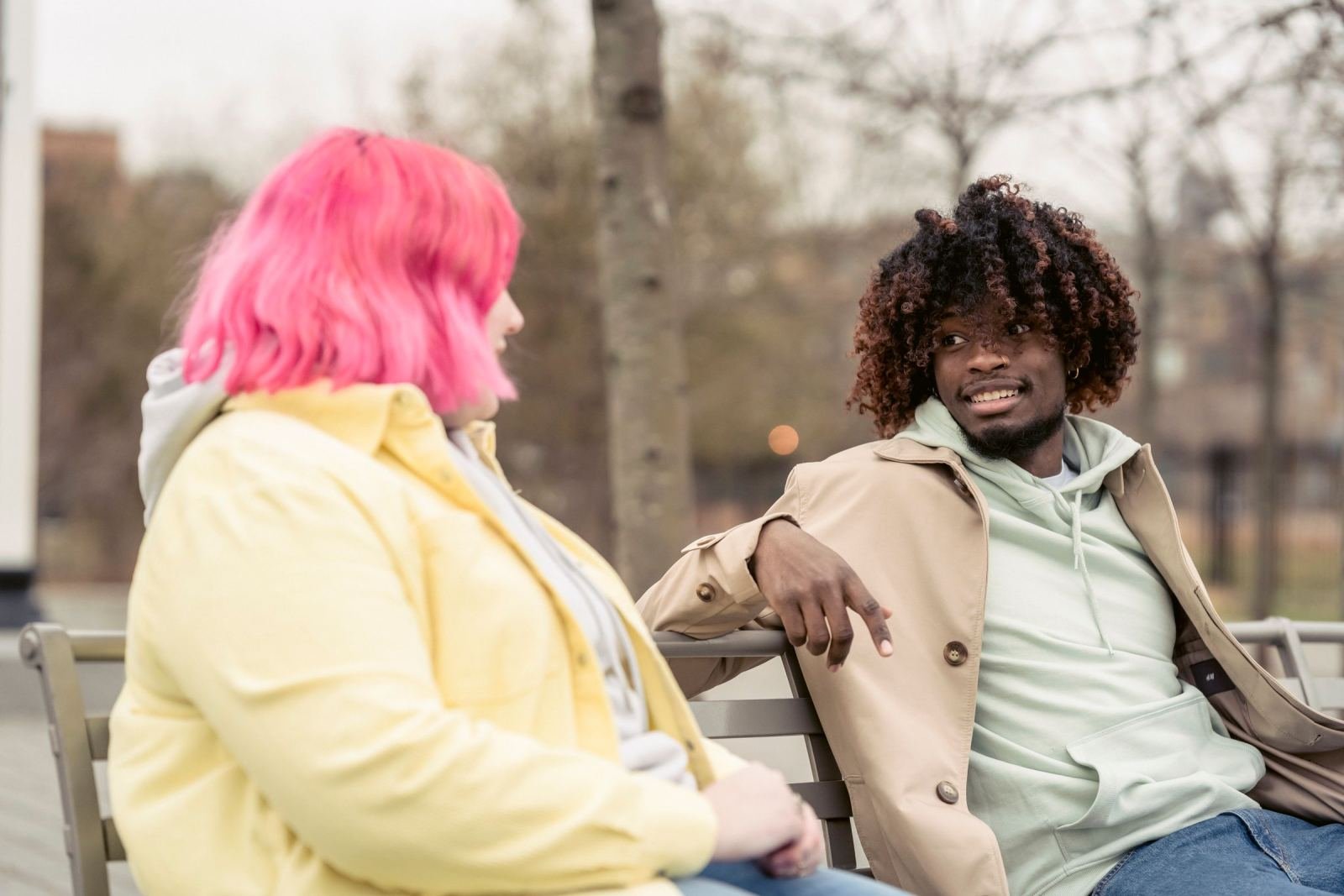 Two people talking together on a park bench in soft light
