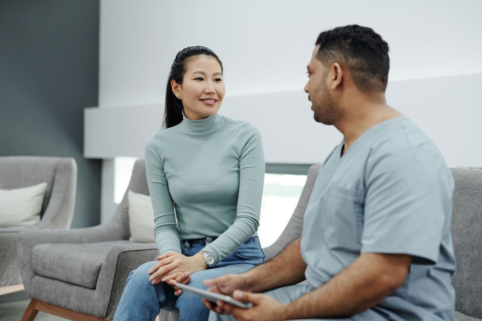 A woman wearing a green shirt is talking with a provider in blue scrubs