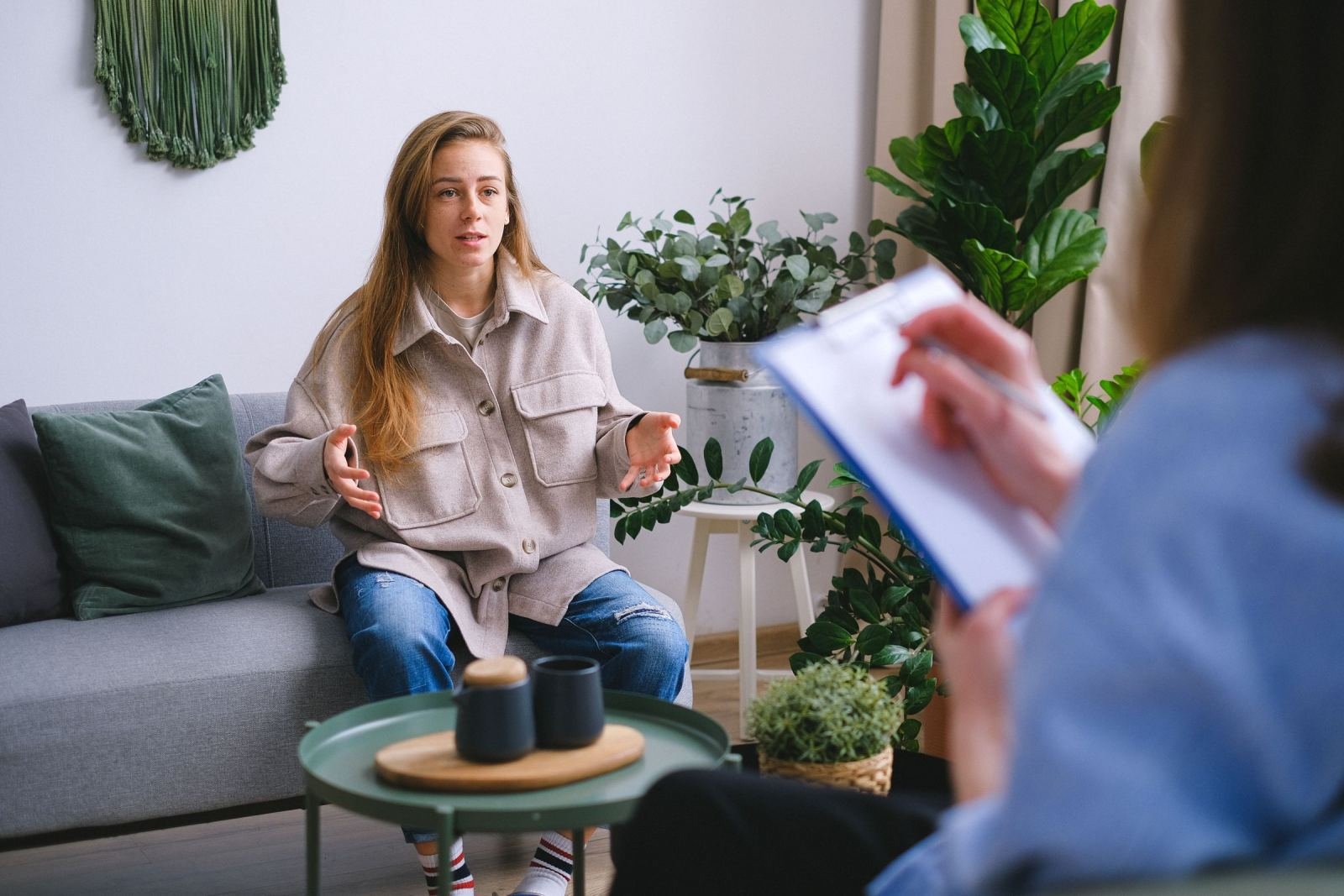 A woman gestures while speaking to a counselor holding a clipboard