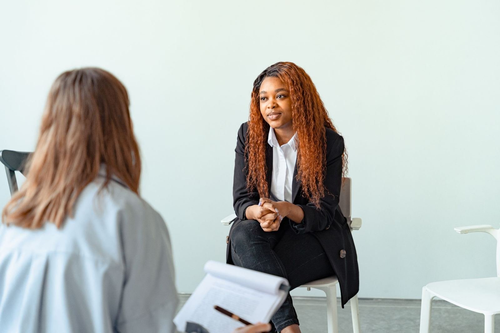 A woman in a black blazer speaks with a provider who is holding a notebook