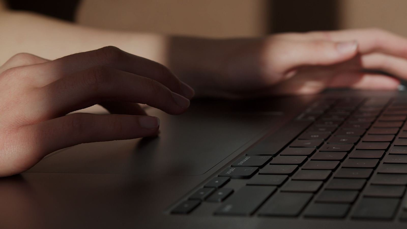 Close-up of a person's hands typing on a laptop keyboard
