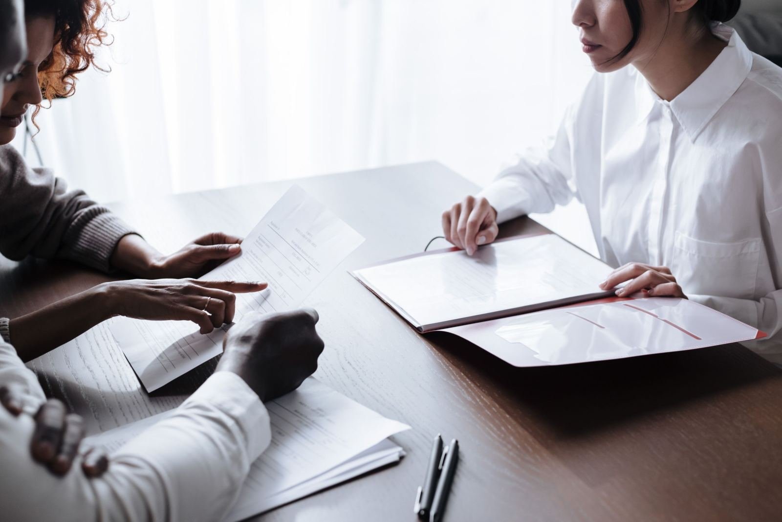 Two people review printed documents together at a wooden table