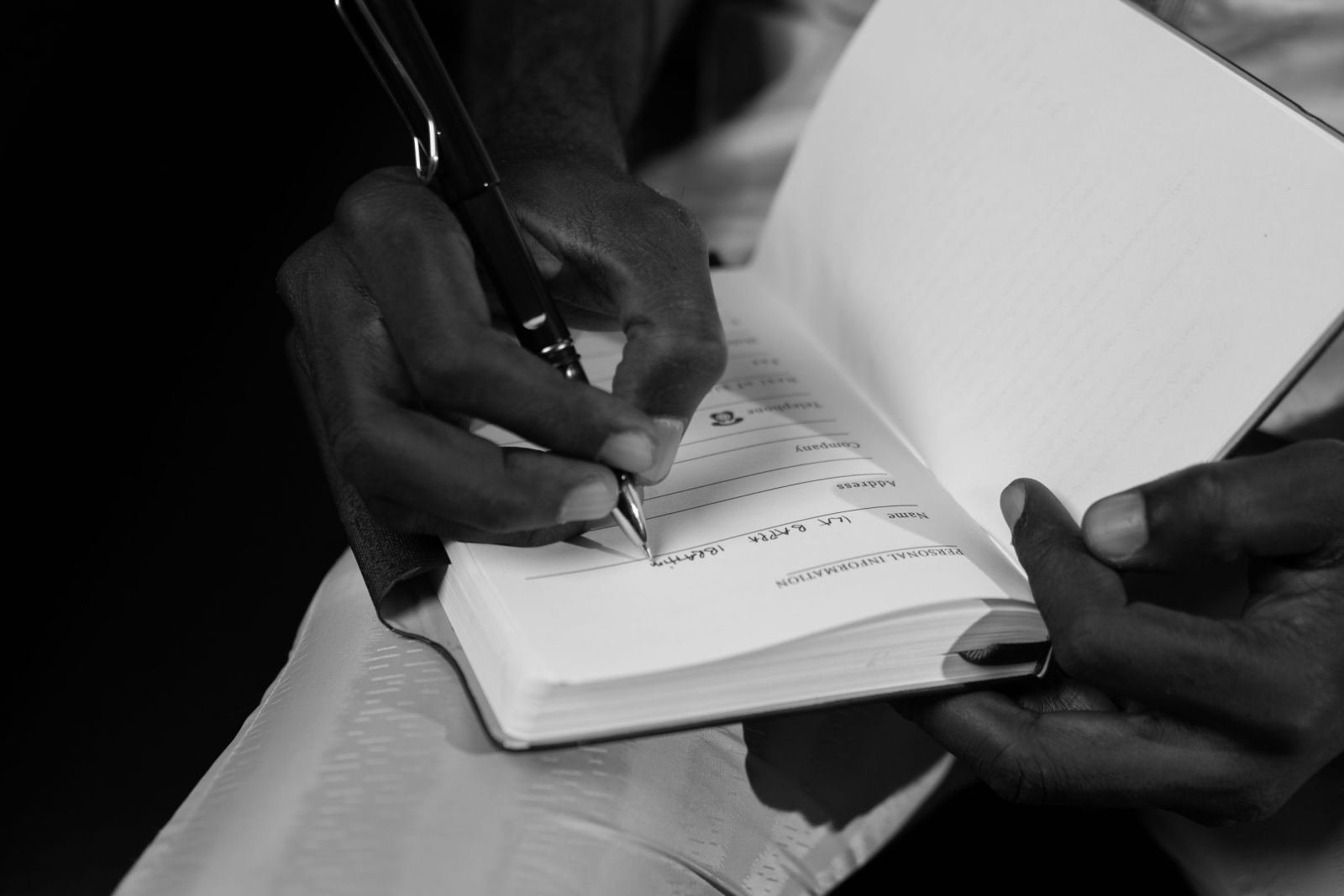 A person fills out personal details in a notebook.