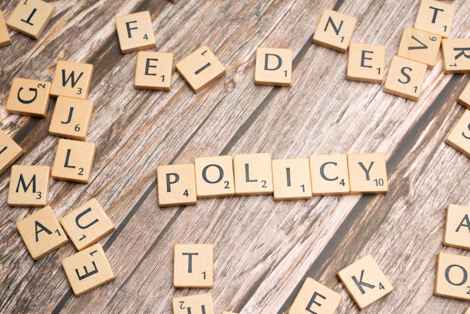 Wooden blocks spell out POLICY on a wood table
